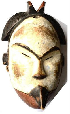 Lot 333 - A Punu Wood Mask of a Woman, with coiffure of central ridge flanked by braided side pieces, the...