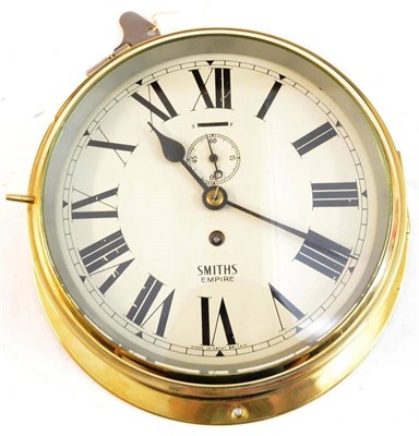 Lot 123 - A Ship's Brass Bulk Head Timepiece by Smiths, the 20cm cream enamel dial with black roman...