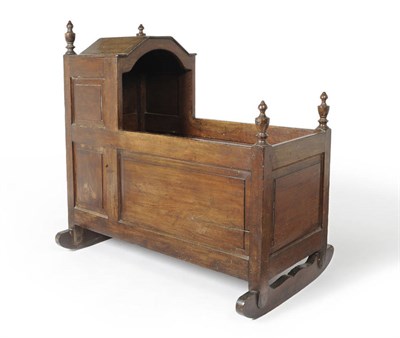 Lot 517 - An 18th Century Joined Oak Cradle, the boarded canopy top with turned finials, fielded panel sides