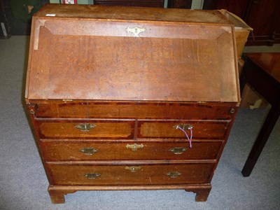 Lot 547 - A George III Oak and Mahogany Crossbanded Bureau, circa 1800, the fall enclosing a fitted...