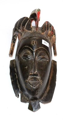 Lot 461 - A Baule Wood Mask, with painted hornbill headdress, slit eyes and pursed lips, 53cm