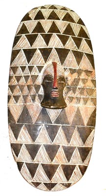 Lot 473 - A Songye DRC Wood Shield, of vertical oblong form, carved with a raised central mask on a...