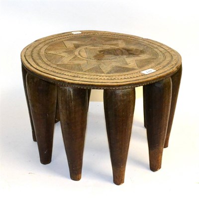 Lot 477 - A Nupe (Nigeria) Wood Stool, the circular top carved with geometric devices, on ten tapering...