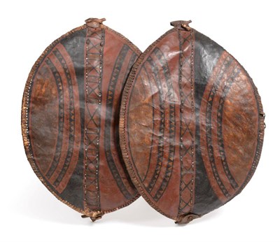 Lot 413 - Two Masai Hide Shields, each of elliptical form, painted with curved bands of diapering and...