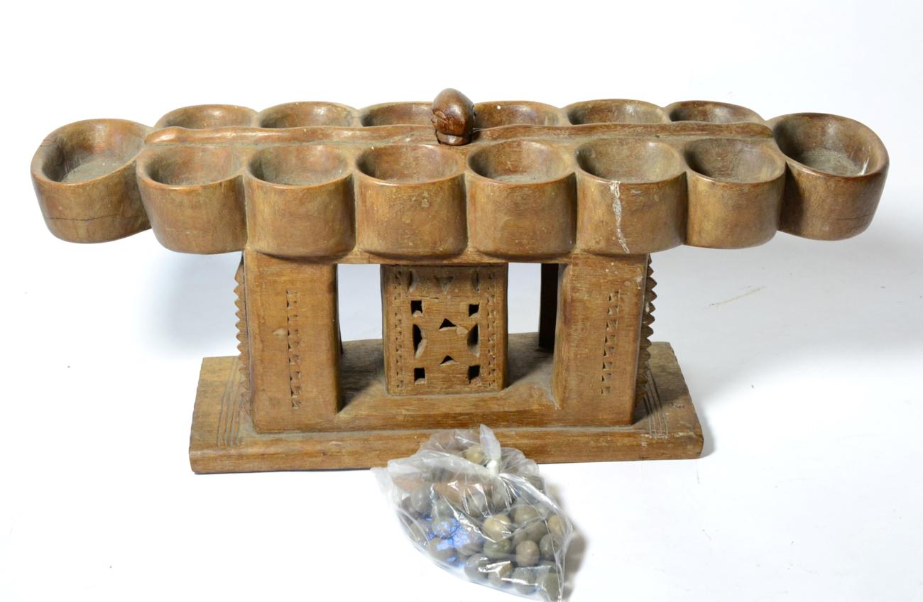 Lot 451 - An Ashanti (Southern Ghana) Oware Strategy Game, with carved wood board of stool form and clay...