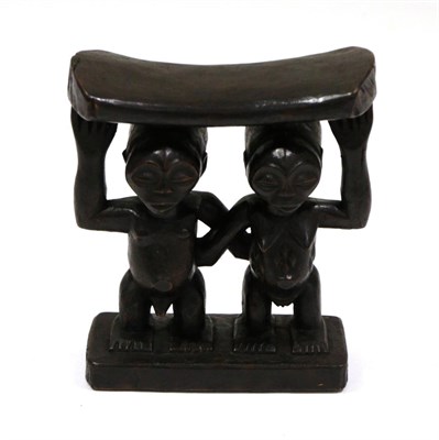 Lot 459 - A Luba Wood Headrest, the curved pillow resting on the heads of a man and woman standing side...