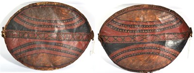 Lot 254 - Two Masai Hide Shields, each of elliptical form, painted with curved bands of diapering and...