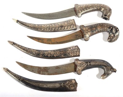 Lot 256 - Three Indian Small Daggers, each with faux damascined curved steel blade, the hilt modelled as...