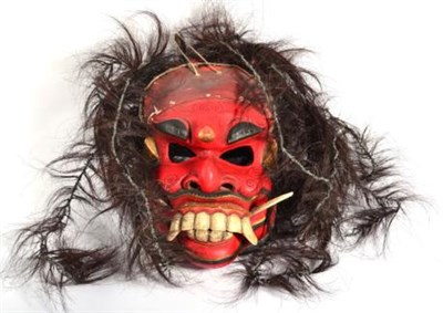 Lot 391 - An Indonesian/Japanese Demon Mask, of red painted palmwood, with animal hair coiffure, pierced eyes