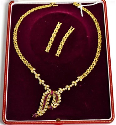 Lot 41 - A ruby and diamond necklace, a scroll front with channel set calibré cut ruby ribbons, with...