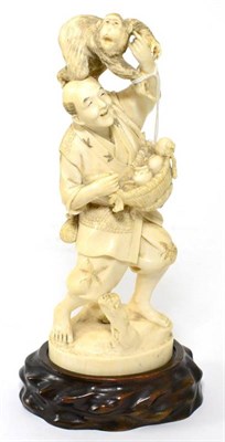 Lot 259 - A Japanese Ivory Okimono, Meiji period, as a farmer carrying a basket of fruit, a monkey on his...