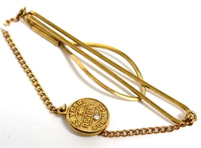 Lot 323 - A 9 carat gold tie clip with a diamond set twenty five years service medal, 8.1g