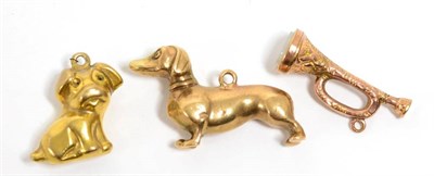 Lot 335 - A 9 carat gold Dachshund charm, another 9 carat gold dog charm and a hardstone set trumpet...