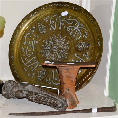 Lot 384 - An Oriental head rest; a Middle Eastern silver inlaid brass tray; and a carved candle holder...