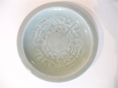 Lot 223 - A Chinese Celadon Circular Dish, Qing Dynasty, carved with a strapwork roundel within a wave...