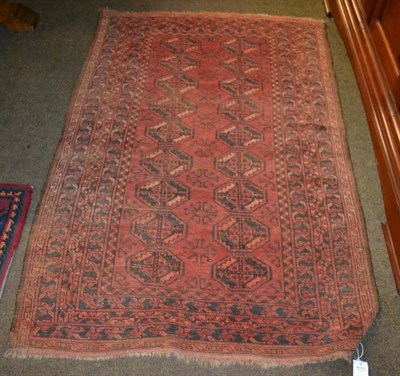 Lot 1437 - A red ground rug, the central field with two columns of octagonal guls