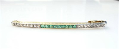 Lot 283 - A French Emerald and Diamond Bar Brooch, nine calibré cut emeralds to the centre of a row of...
