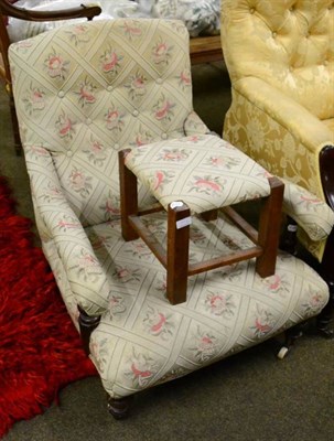 Lot 1552 - An Edwardian upholstered open armchair of Howard style with a later footstool, upholstered to match