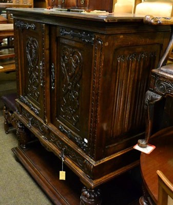 Lot 1593 - A 1920/30s carved oak cupboard, with parquetry decorated top and linen fold side panels, the...