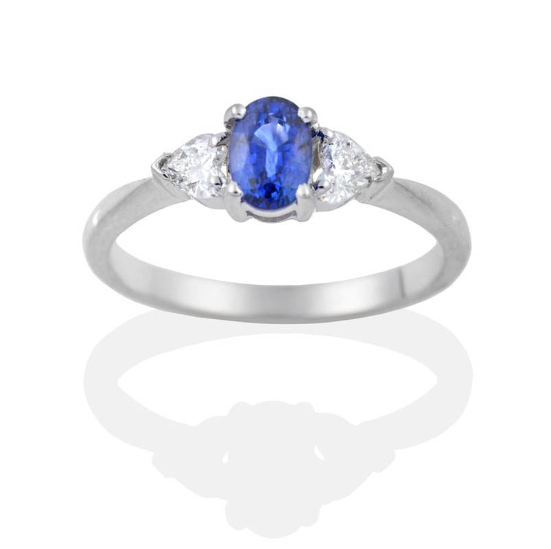 Lot 2035 - An 18 Carat White Gold Sapphire and Diamond Three Stone Ring, an oval cut sapphire spaced by...