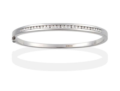 Lot 2051 - An 18 Carat White Gold Diamond Bangle, the front channel set with round brilliant cut diamonds to a