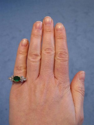 Lot 2113 - An 18 Carat Gold Emerald and Diamond Ring, an oval cut emerald in a rubbed over setting and...