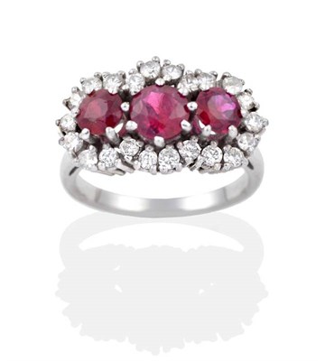 Lot 2186 - A Ruby and Diamond Cluster Ring, three graduated round cut rubies within a border of round...