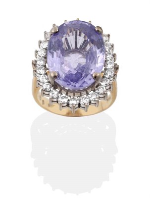 Lot 2195 - A Violet Sapphire and Diamond Cluster Ring, an oval cut violet sapphire within a border of...