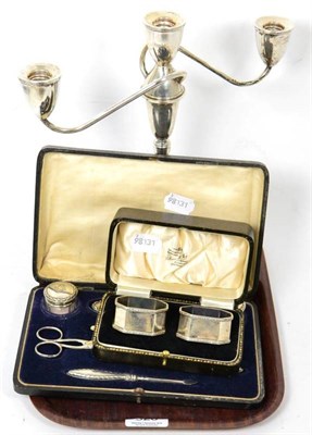 Lot 326 - A silver three piece candelabra; cased silver napkin holders; and a cased silver manicure set