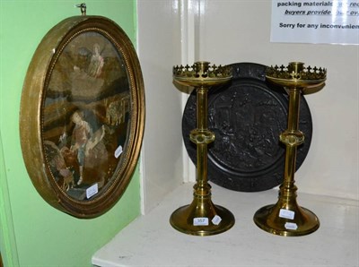 Lot 357 - A pair of Gothic brass candlesticks; a George III needlework picture; and a cast iron charger...