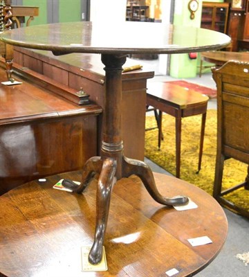 Lot 1361 - A mahogany tripod table, 18th century in part, with circular fliptop on a gun barrel support...