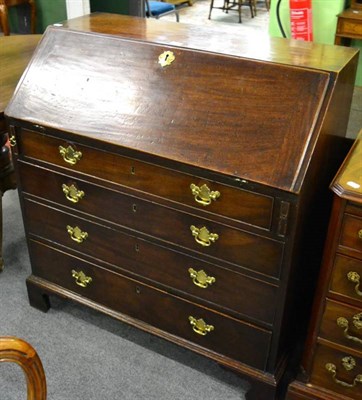 Lot 1387 - A George III mahogany bureau on bracket feet with four graduating drawers, brass handles and...