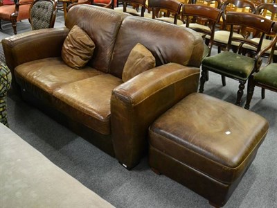 Lot 1398 - A brown leather two seater sofa and matching footstool