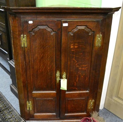 Lot 1457 - A George III oak panelled corner cupboard