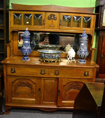 Lot 1473 - An Arts & Crafts oak mirror backed sideboard, the upper section with glazed cupboard doors