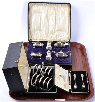 Lot 89 - A pair of silver toast racks, Sheffield 1933, cased; a six piece condiment set, in a fitted...