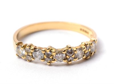 Lot 100 - An 18 carat gold diamond half hoop ring, of round brilliant cut diamonds spaced by pairs of smaller