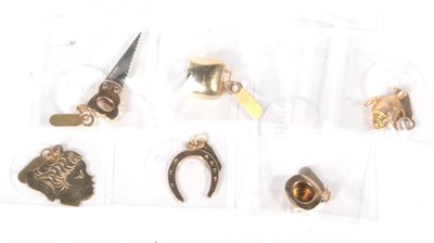 Lot 527 - Six various 9 carat gold charms, including; a horseshoe, a face, a teapot, a top hat, a saw and...