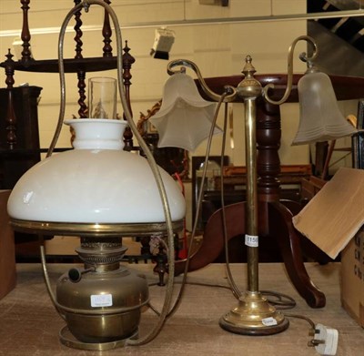 Lot 1159 - ~ An early 20th century brass table lamp with two scroll arms and frosted glass shades;...