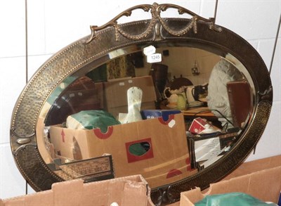 Lot 1245 - ~ An early 20th century oval bevel glass mirror, the beaten copper frame surmounted by acanthus...