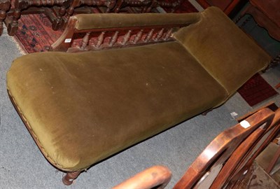 Lot 1366 - ~ A late Victorian chaise longue upholstered in green velvet with a spindle turned arm support...