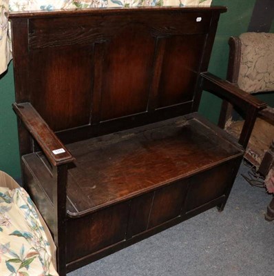 Lot 1374 - ~ An early 20th century oak panelled box settle, with fielded back support above a hinged seat...