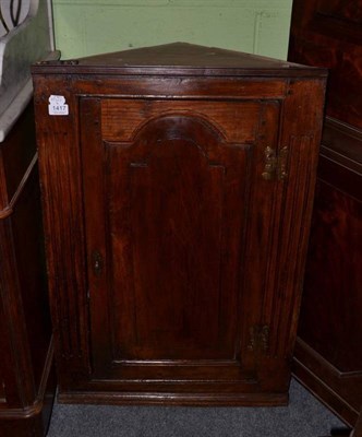 Lot 1417 - An 18th century oak hanging corner cupboard, with moulded arched cupboard door enclosing a...