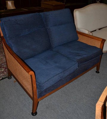 Lot 1471 - Parker knoll two seater sofa with cane sides and blue upholstered cushions, 132cm wide