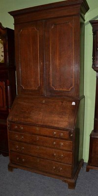 Lot 1562 - ~ A George III oak bureau bookcase, late 18th century, with a dentil cornice above two cupboard...