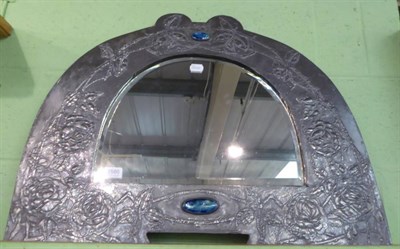 Lot 1580 - ~ An early 20th century Liberty style pewter mirror, the arched frame decorated with leaves and...