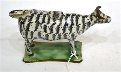 Lot 303 - A Pearlware Cow Creamer and Stopper, circa 1810, with black and white striped markings, on a...