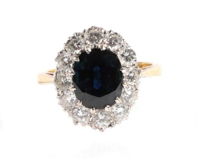 Lot 582 - An 18 Carat Gold Sapphire and Diamond Cluster Ring, an oval cut sapphire within a border of...