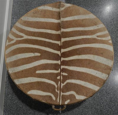 Lot 1112 - A large circular Zebra hide drum table, circa 1960-70, of circular form raised upon three feet,...