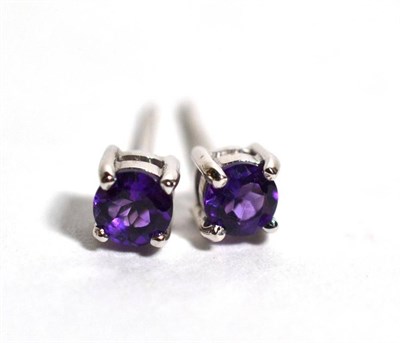 Lot 67 - A pair of 18 carat white gold amethyst stud earrings, a round  cut amethyst in a claw setting,...
